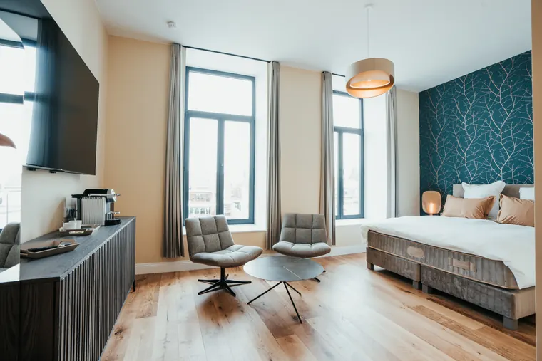Chambre Prestige — vue d'ensemble : commode basse, fauteuils pivotants et double fenêtre lumineuse