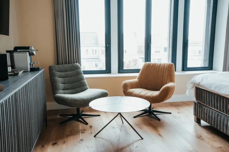 Chambre Prestige — coin salon devant la grande verrière, avec vue sur le village