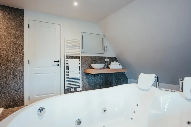 Suite Elite — baignoire balnéo deux places et vasque sur plan en bois, sous la lucarne